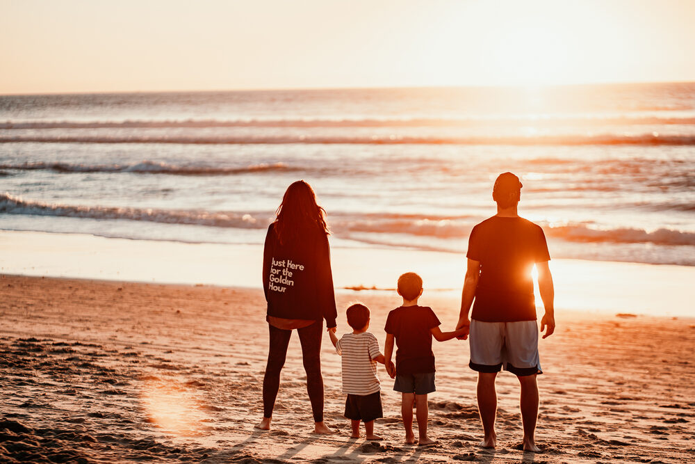 Family silhouettes watching sunset at the beach